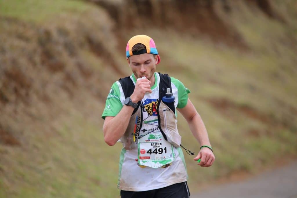 coureur en compétition de trail en train de boire sa flasque d'eau.