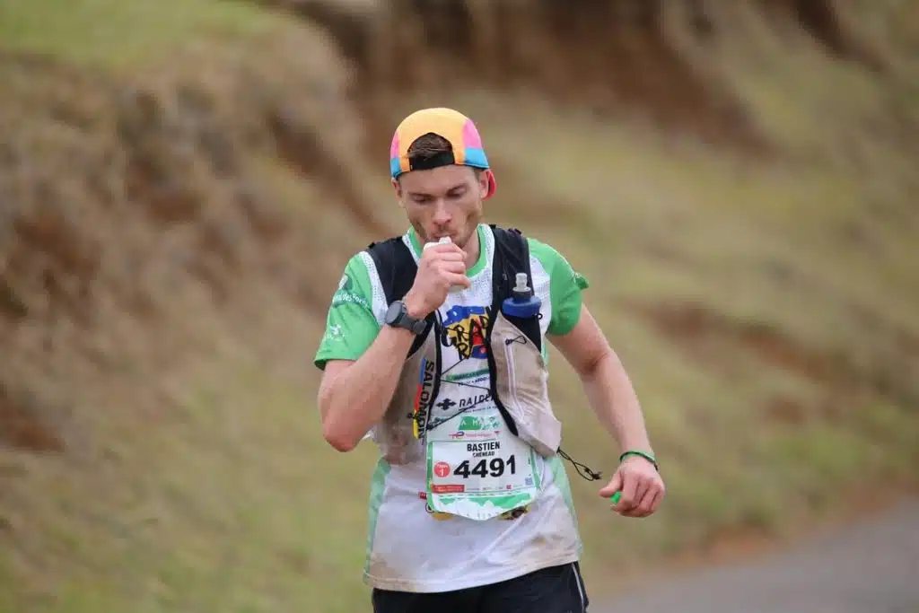 coureur en compétition de trail en train de boire sa flasque d'eau.